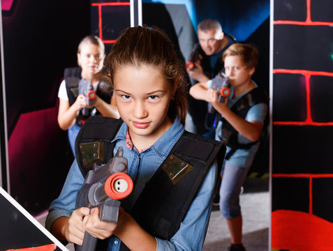 Portrait of teenager girl with laser gun having fun with her family on lasertag arena