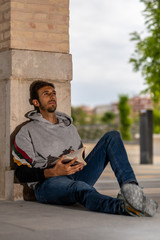 Young Bearded Man Reading A Book Sitting In A Park During The Morning.