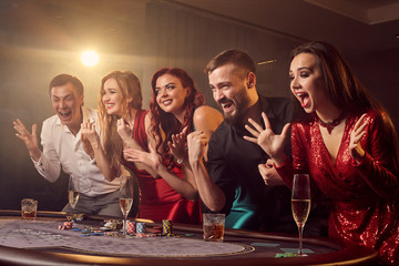 Group of a young rich friends are playing poker in casino.