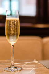 A glass of Champagne puts on marble table in restaurant for celebration with blurred background.