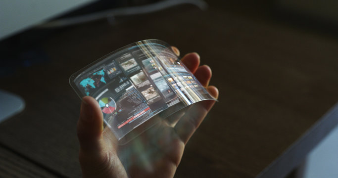 Close up of a woman hand is using a futuristic liquid crystals cell phone with the latest advanced augmented reality holographic technology.