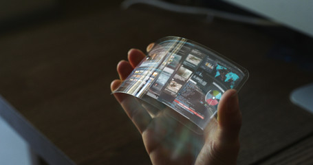 Close up of a woman hand is using a futuristic liquid crystals cell phone with the latest advanced augmented reality holographic technology.