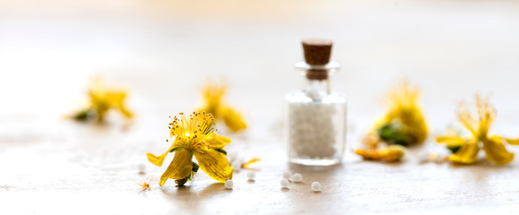 Johanniskraut in der Homöopathie-Glasfläschchen mit Globulis und Johanniskrautblüten