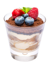Classic tiramisu dessert with blueberries and raspberries in a glass isolated on a white background with clipping path
