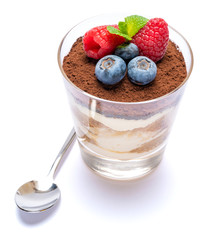 Classic tiramisu dessert with blueberries and raspberries in a glass isolated on a white background with clipping path