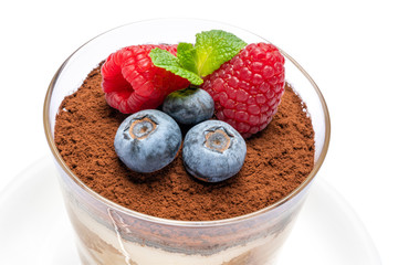 Classic tiramisu dessert with blueberries and raspberries in a glass isolated on a white background with clipping path