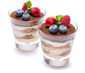 Classic tiramisu dessert with blueberries and raspberries in a glass isolated on a white background with clipping path