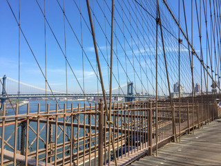 Manhattan bridge view from Brooklyn Bridge with wire and blue sky background, New York City.