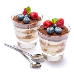 Classic tiramisu dessert with blueberries and raspberries in a glass isolated on a white background with clipping path