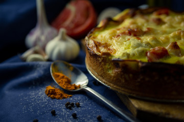 delicious open French cake with chicken cauliflower onion garlic egg cream tomato pepper turmeric baked in oven on table blue cloth sieve flour