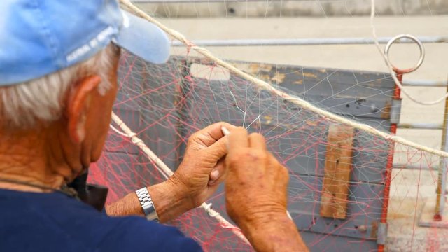 Old fisherman reparing fishing net.