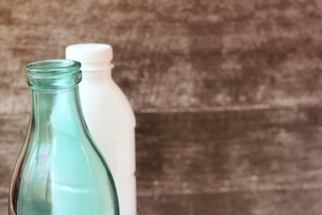 Glass milk bottle and plastic bottle. Reusable packaging. Empty space for text.