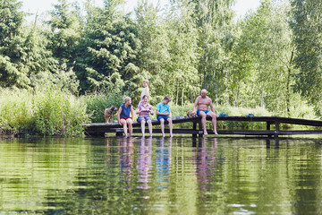 Family sitting on a bridge over a lake during summer vacations