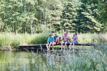 Family sitting on a bridge over a lake during summer vacations