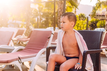 A five-year-old child sits on a sunbed