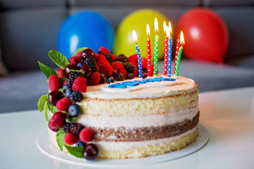 Homemade kids birthday cake with lots of fruits on top, cherries, strawberries, raspberries