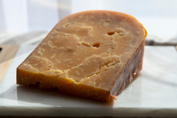 Three years old dark yellow hard Dutch cheese in sun lights