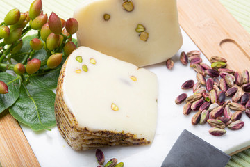 Italian provolone or provola cheese made in Sicily with tasty green Bronte pistachio nuts served on white marble plate close up