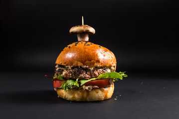 Tasty burger with grilled meat and mushroom on the black background