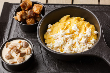 Typical Ukrainian dish polenta - Banosh with cheese and lard. Ukrainian cuisine. maize porridge with bacon, cracklings and cheese Corn porridge in plate on wooden background.