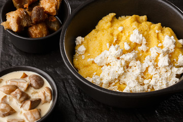 Typical Ukrainian dish polenta - Banosh with cheese and lard. Ukrainian cuisine. maize porridge with bacon, cracklings and cheese Corn porridge in plate on wooden background.