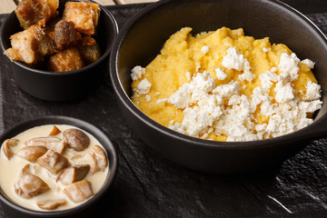 Typical Ukrainian dish polenta - Banosh with cheese and lard. Ukrainian cuisine. maize porridge with bacon, cracklings and cheese Corn porridge in plate on wooden background.