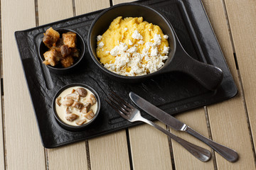 Typical Ukrainian dish polenta - Banosh with cheese and lard. Ukrainian cuisine. maize porridge with bacon, cracklings and cheese Corn porridge in plate on wooden background.