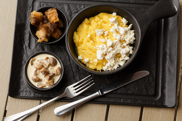Typical Ukrainian dish polenta - Banosh with cheese and lard. Ukrainian cuisine. maize porridge with bacon, cracklings and cheese Corn porridge in plate on wooden background.