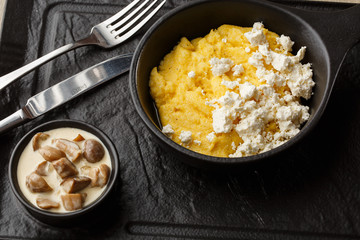 Typical Ukrainian dish polenta - Banosh with cheese and lard. Ukrainian cuisine. maize porridge with bacon, cracklings and cheese Corn porridge in plate on wooden background.