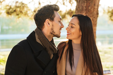 Naklejka premium Happy young beautiful loving couple posing walking outdoors in park nature kissing.