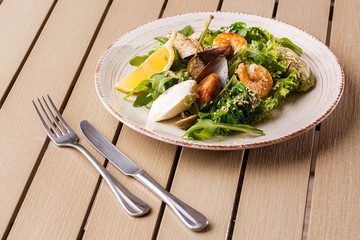 Healthy Salad. Recipe for fresh seafood. Grilled shrimps, mussels and squid, fresh salad lettuce and avocado puree. Healthy Eating. Wooden background