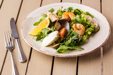 Healthy Salad. Recipe for fresh seafood. Grilled shrimps, mussels and squid, fresh salad lettuce and avocado puree. Healthy Eating. Wooden background