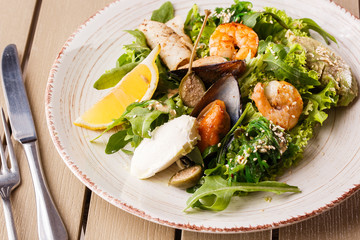 Healthy Salad. Recipe for fresh seafood. Grilled shrimps, mussels and squid, fresh salad lettuce and avocado puree. Healthy Eating. Wooden background