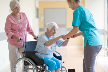 Nurse helping elderly woman in wheelchair