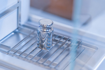 Stainless steel calibration weight to place on the analytical balance for calibration test.