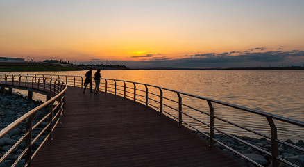Fototapeta na wymiar A couple on the bridge by the lake at sunset