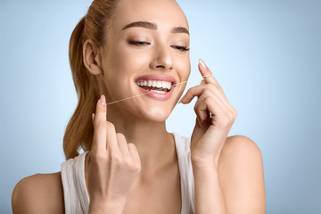 Woman Using Dental Floss Over Blue Background