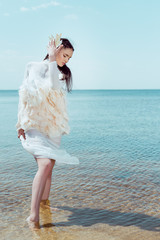 beautiful woman in white swan costume standing on sand bottom © LIGHTFIELD STUDIOS