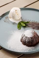 Delicious fresh fondant with hot chocolate and ice cream and mint served on plate. Lava cake recipe. Wooden background.