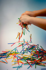 Hand letting coloured wooden  sticks drop on white