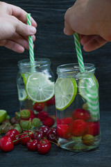 Refreshing summer drink with fruit. Drink made from cherry, gooseberry, lime. Dark wooden background.