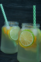Refreshing summer drink from citrus fruits. Drink from lime, lemon, orange. Dark wooden background.