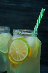 Refreshing summer drink from citrus fruits. Drink from lime, lemon, orange. Dark wooden background.