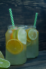 Refreshing summer drink from citrus fruits. Drink from lime, lemon, orange. Dark wooden background.