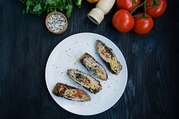 Baked chicken rolls with cheese, greens served on a white plate. Fresh vegetables. Dark wooden background.