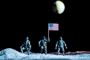 toy soldier holding national american flag in space with planet Earth on black background