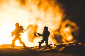 toy soldiers silhouettes with guns on planet with sun in smoke on background