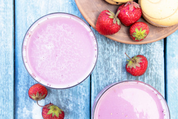 Cocktail with milk and berries club in a glass against the background of blue boards.