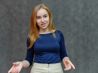 Concept portrait portrait of a beautiful smiling girl woman with red hair in a blue jacket. Something tells on a dark gray background. Shows emotions. Made in a studio.