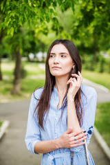 A girl of Asian appearance on a walk in a city park. Summer portrait of young Tatar on a background of green foliage